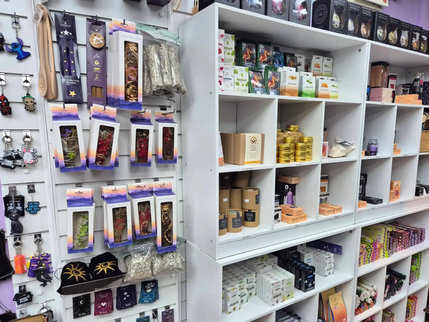 White shelving unit with multiple compartments displaying various products like candles, incense, and decorative items