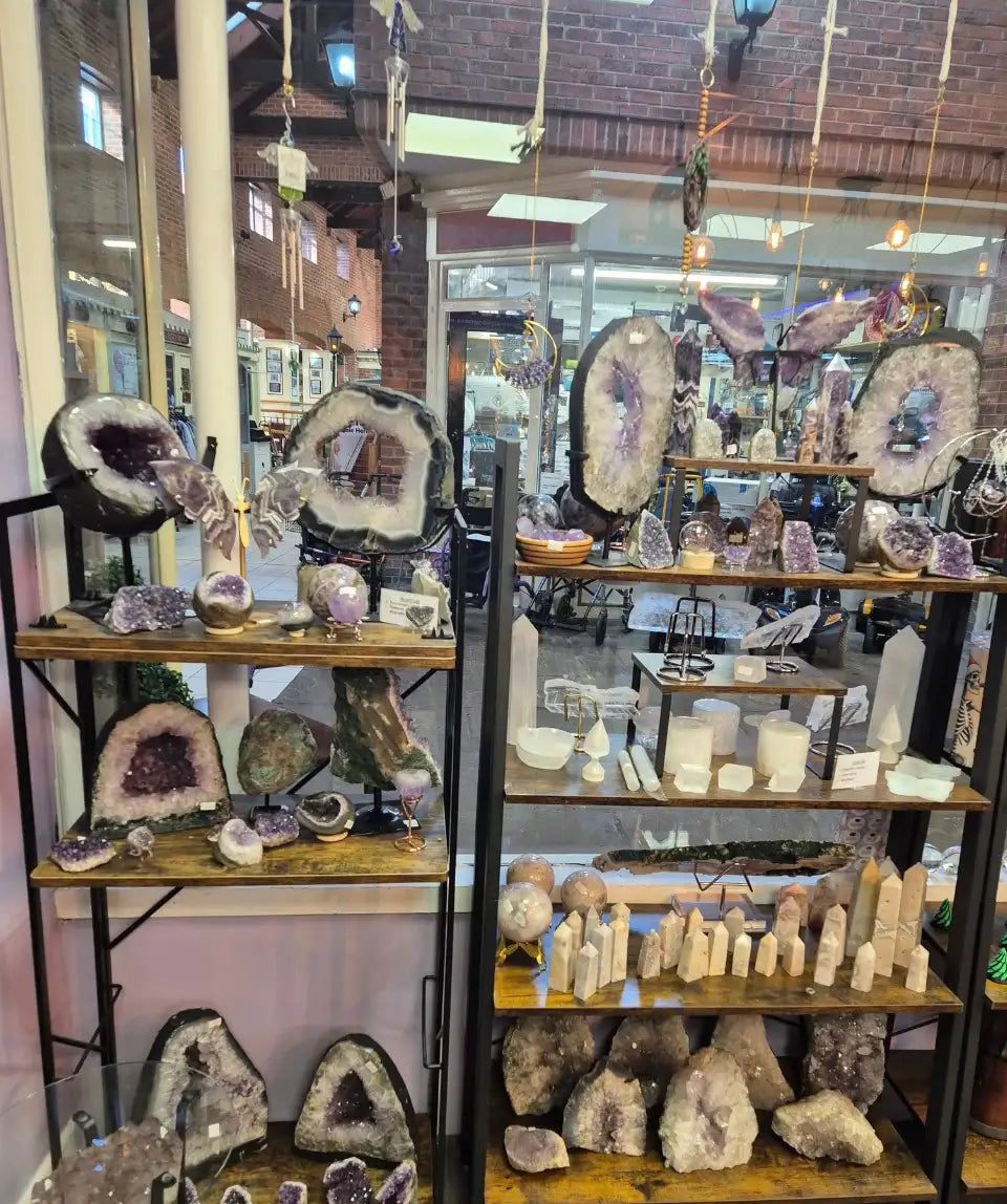 Purple amethyst geodes with sparkling crystalline interiors displayed on wooden shelves.